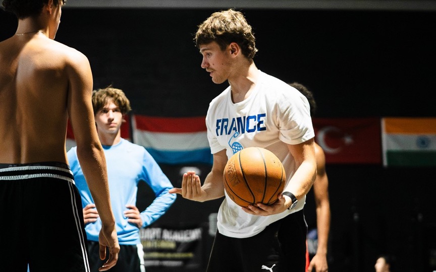 A coach teaching a drill to his players on the court